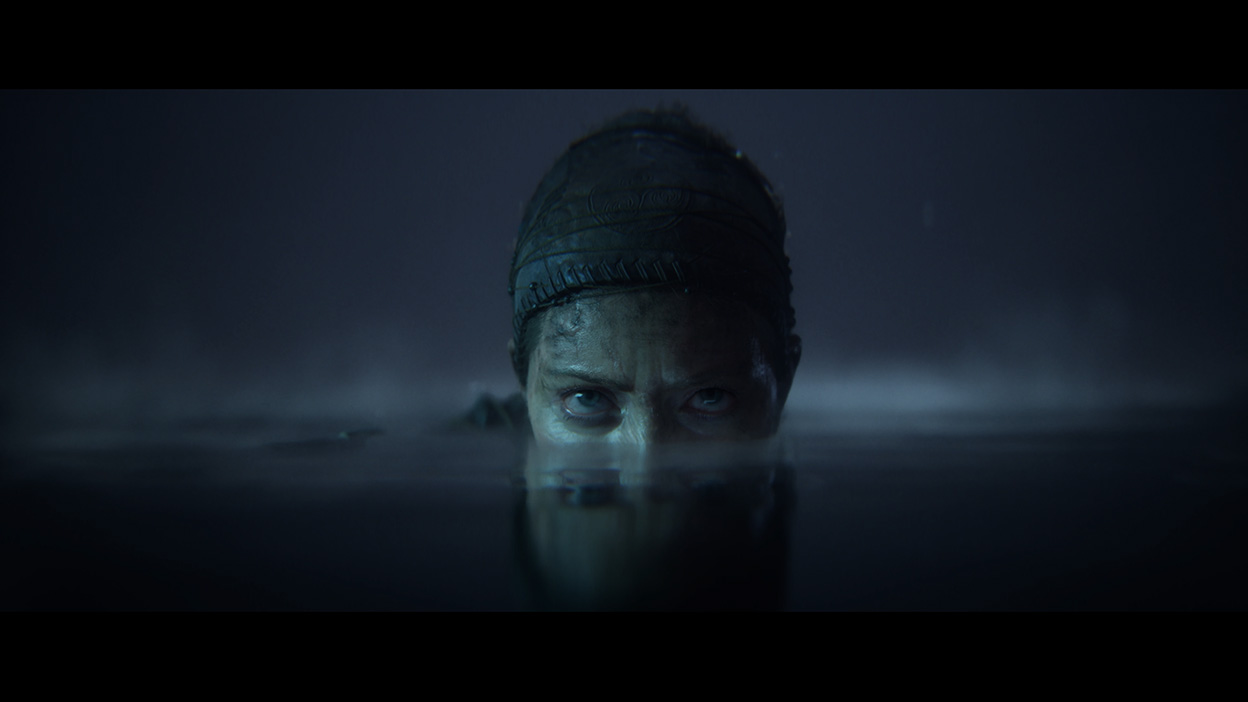 Senua regarde sous l’eau dans une grotte sombre.