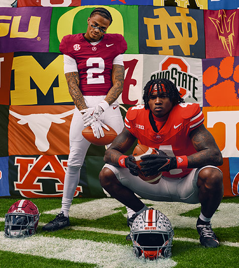 American football players posing on a football field in front of a banner featuring dozens of US college team logos.
