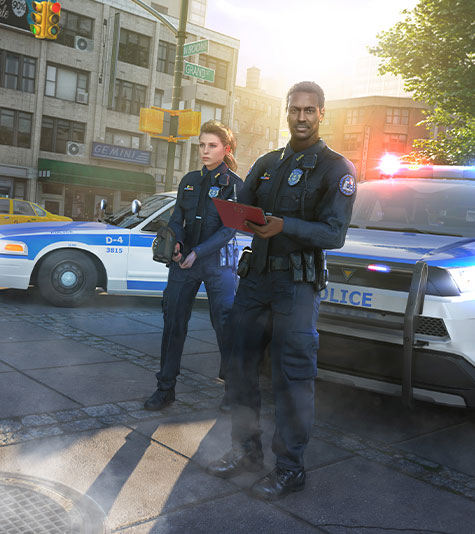 A male and female police officer standing in front of police cars with emergency lights flashing.