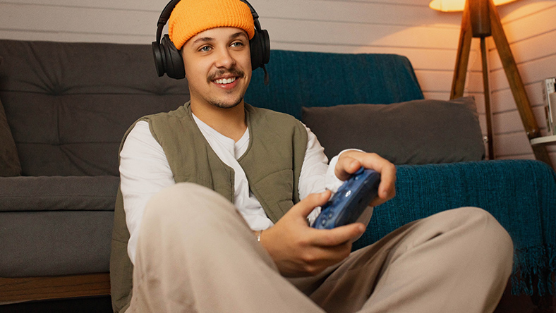 Person sitting in front of a couch with a Xbox Wireless Headset and Xbox controller