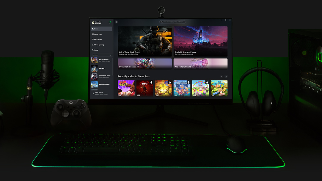 A straight on view of a gaming PC complete with monitor, microphone, Xbox wireless controller, keyboard, mouse, and headset.