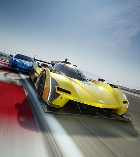A yellow racing car followed closely by a blue racing car speeding down a track on a clear day. 