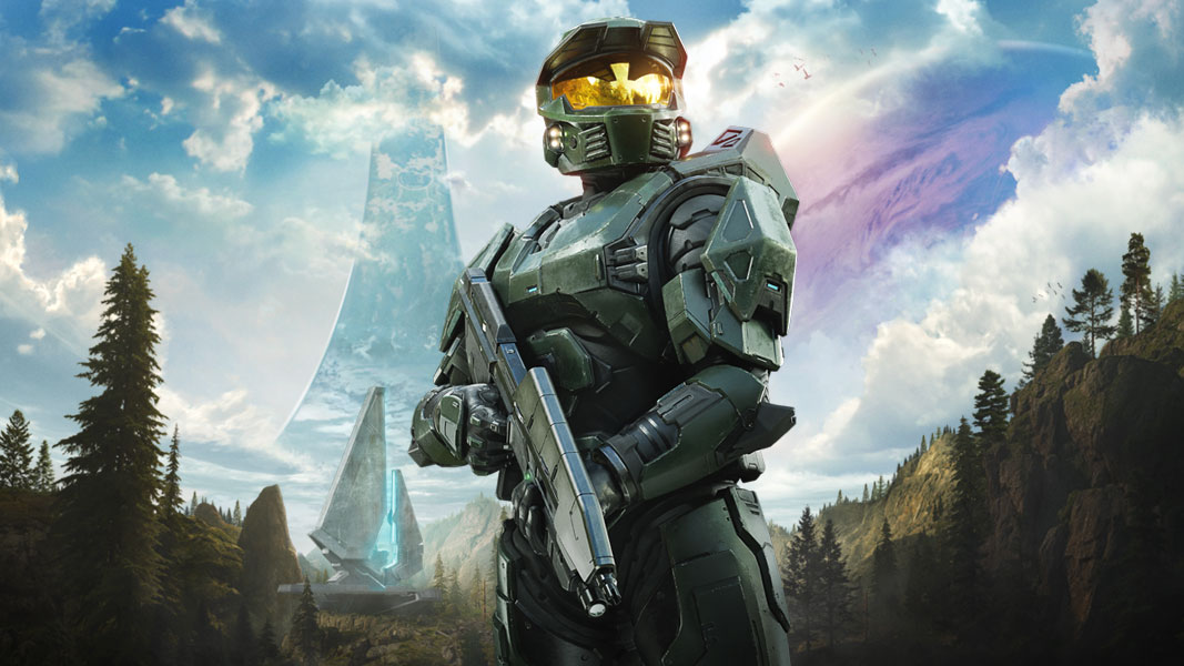 The Master Chief stands holding his weapon with a large futuristic building and a huge planet in the sky in the background.