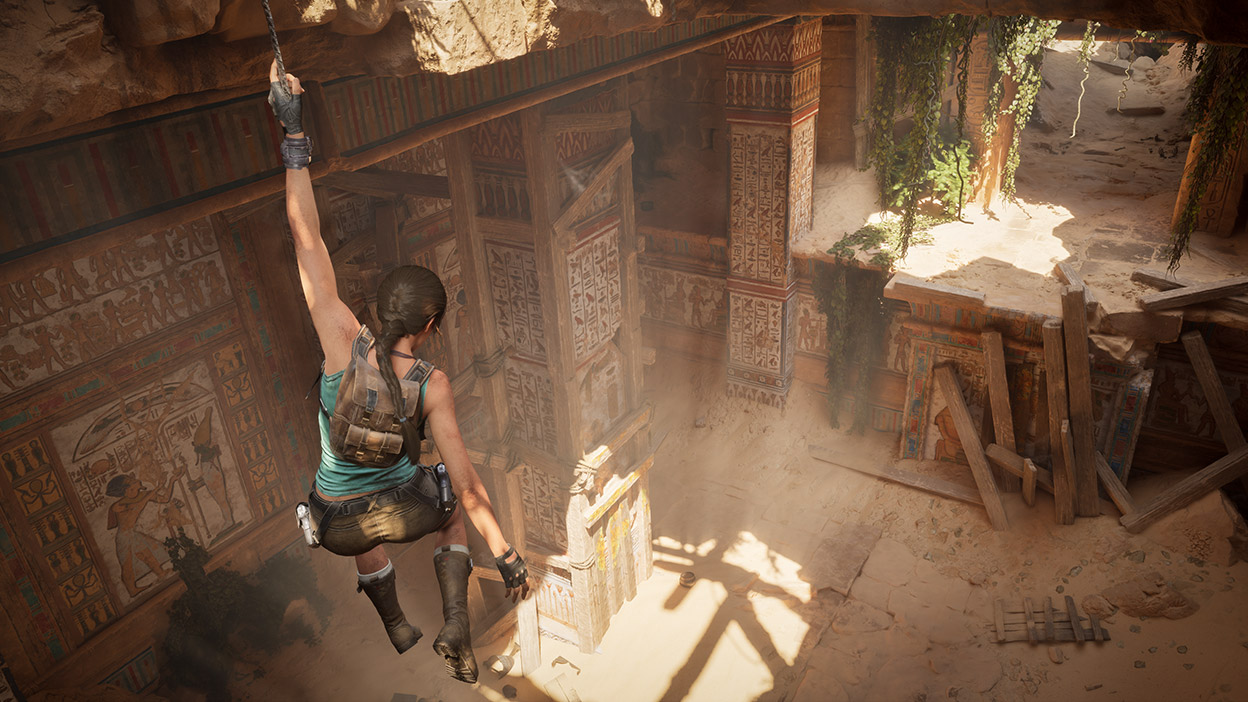 Lara Crofts hangs onto a small rope above the Temple of Khamoon.