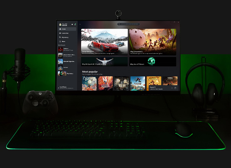 A straight on view of a gaming PC complete with monitor, microphone, Xbox wireless controller, keyboard, mouse, and headset.