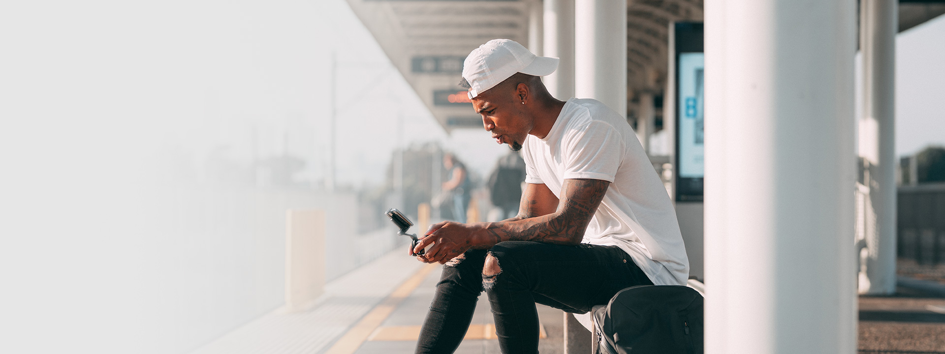 Person playing on a mobile device while waiting for a train