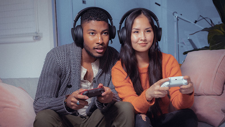 Eine Frau und ein Mann tragen Headsets und spielen ein Spiel mit Xbox-Controllern.