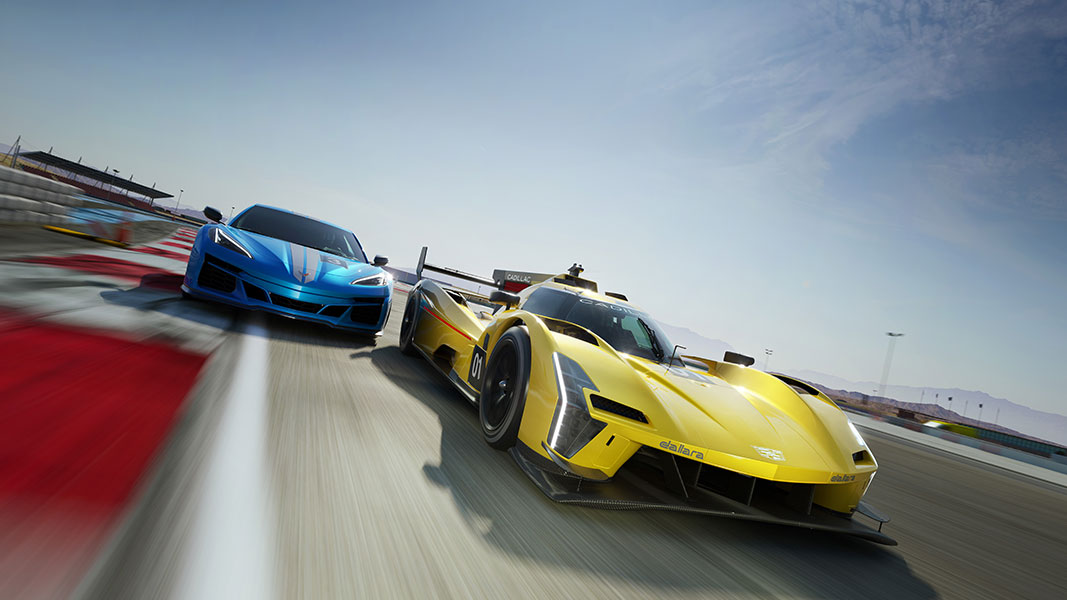 A yellow racing car followed closely by a blue racing car speeding down a track on a clear day. 