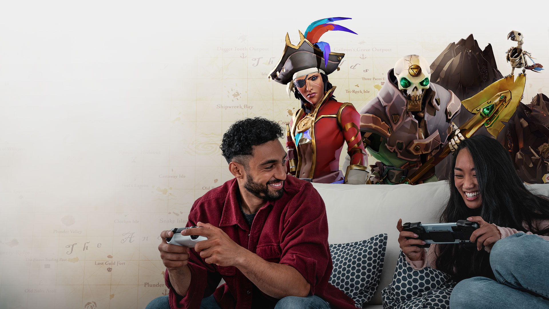 Two people playing on a couch with Sea of Thieves key art in the background