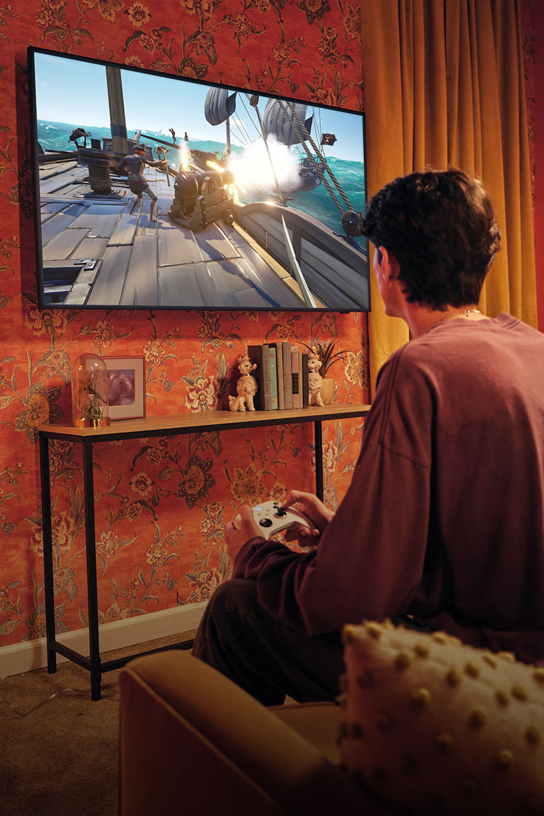 A person sitting in their living room playing Xbox on their TV