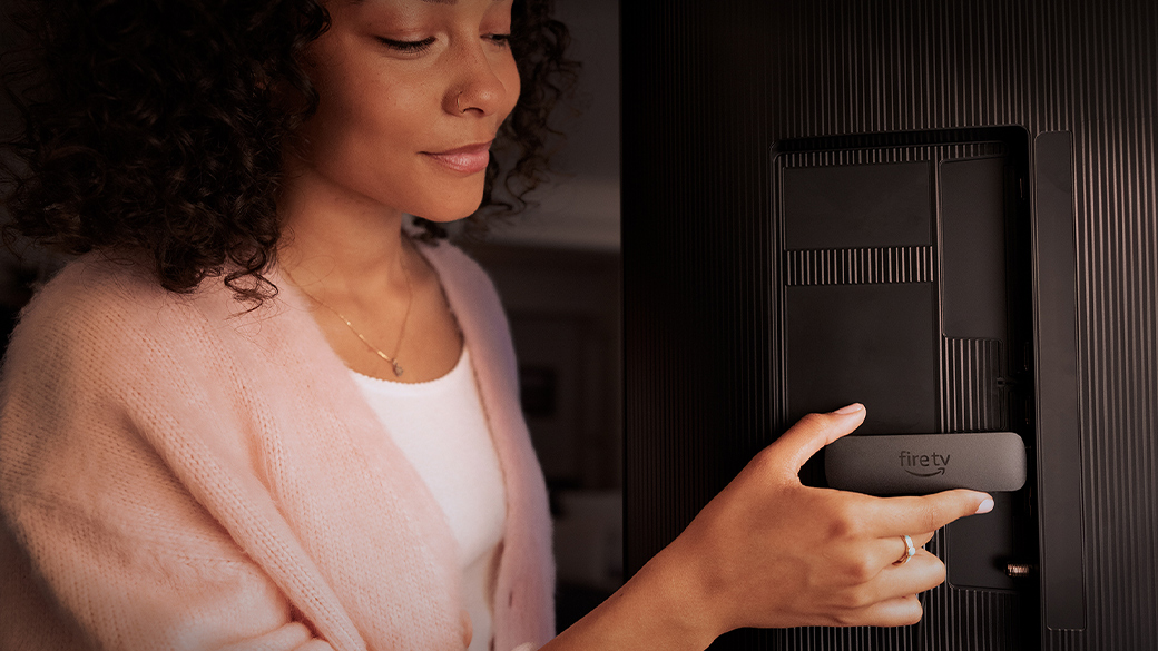Amazon Fire TV Stick をテレビの背面に接続している女性