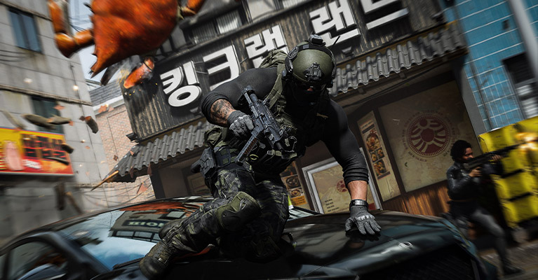 En karaktär i taktisk utrustning håller i ett automatvapen medan han hoppar över motorhuven på en bil framför en koreansk restaurang med en gigantisk krabbskylt.